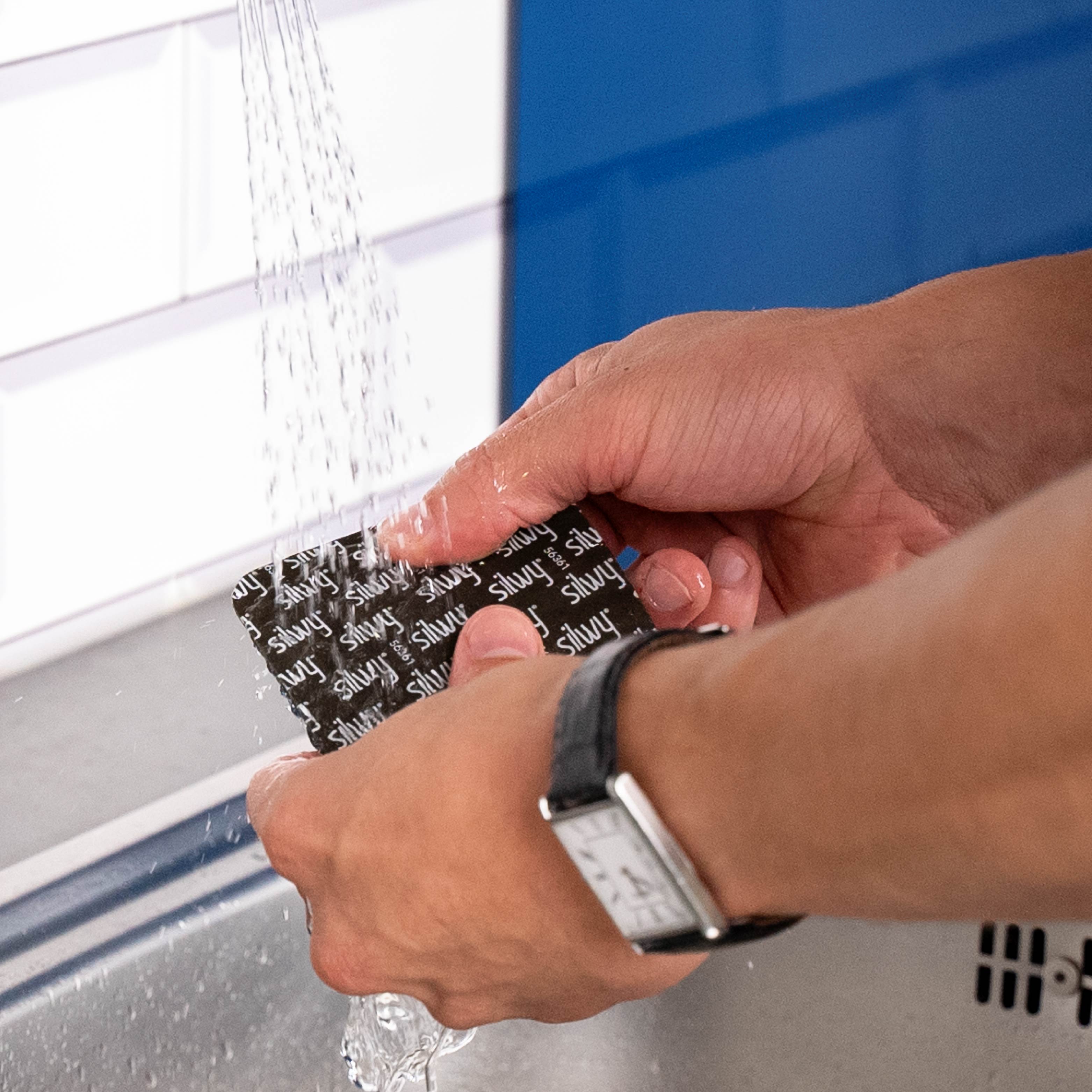 Abwaschen des quadratischen Metall-Nano-Gel-Pads unter klarem Wasser