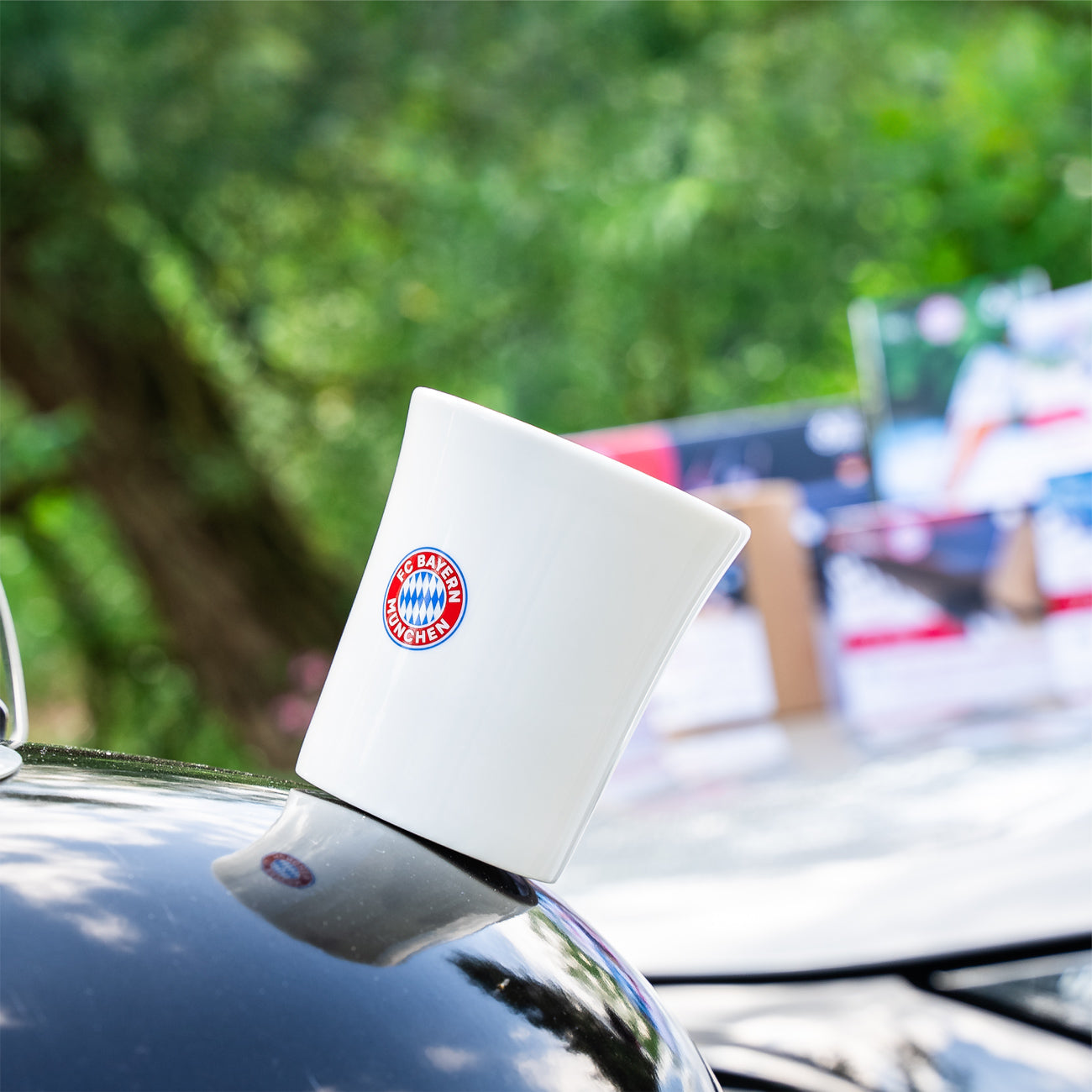 Magnet-Porzellantasse wird durch metallische Motorhaube fixiert, auf Tasse ist FC Bayern Logo
