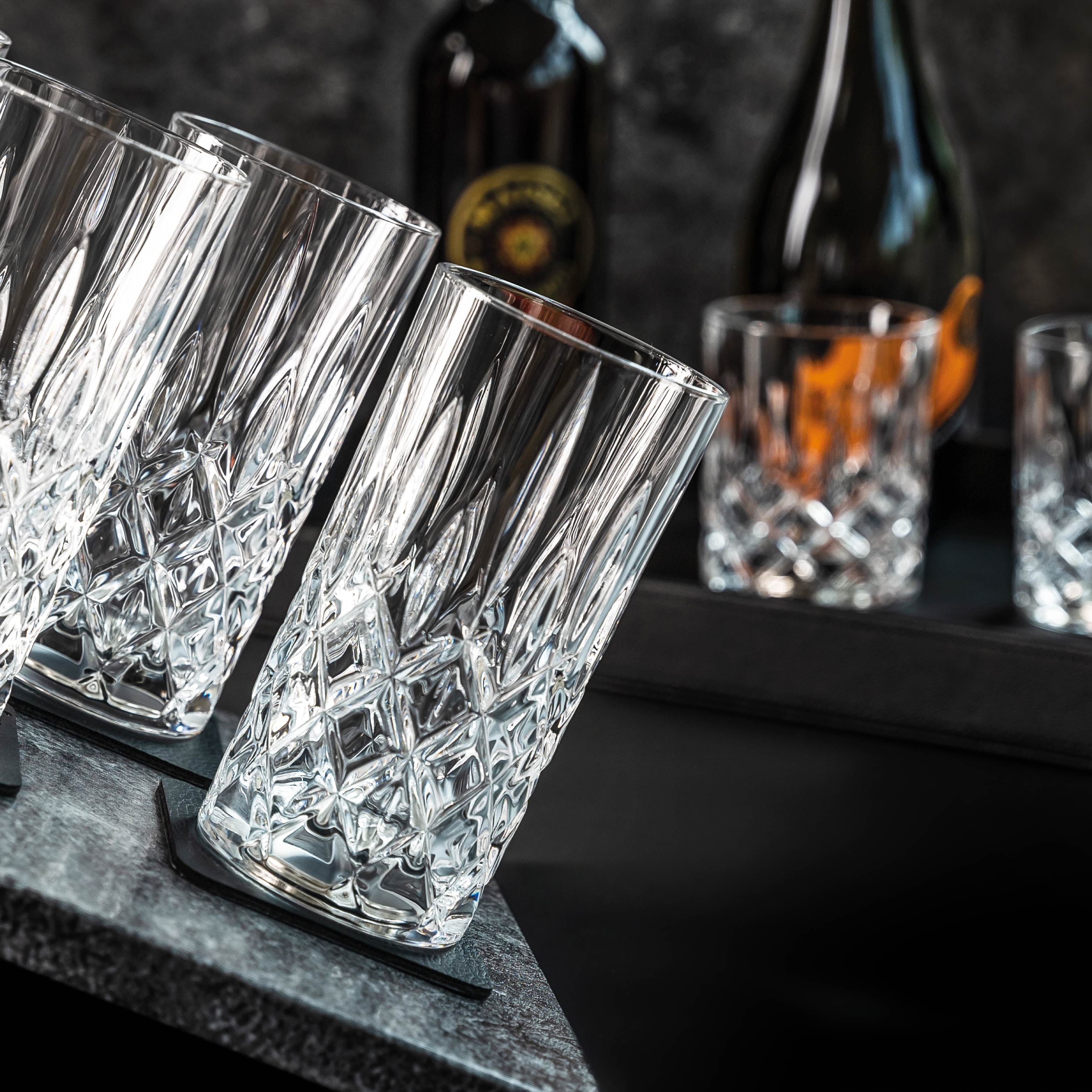 Magnet-Kristallgläser LONGDRINK auf quadratischen Metall-Nano-Gel-Pads auf schiefer Oberfläche und im Hintergrund Magnet-Kristallgläser SHOT