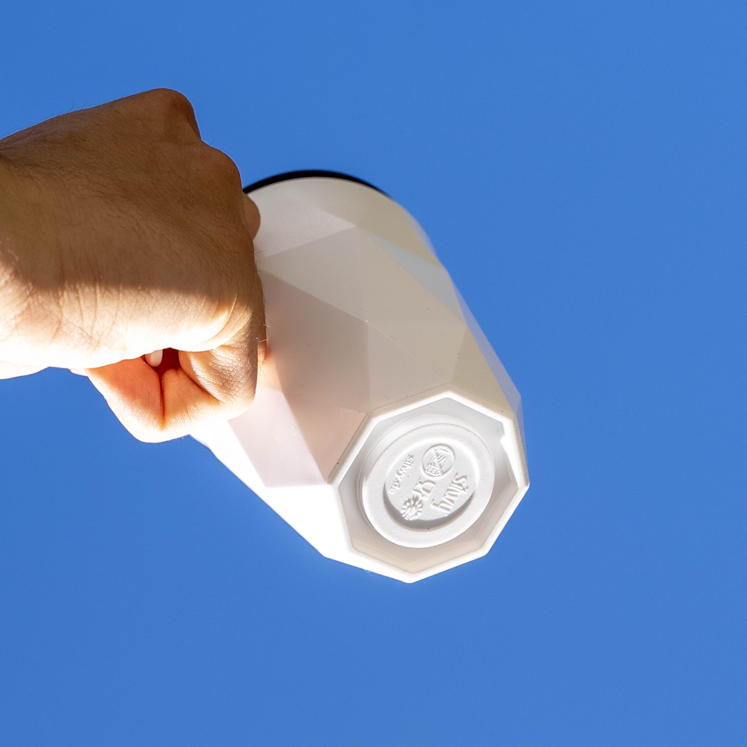 Magnet-Kunststofftasse TO-GO mit integriertem Magneten im Boden vor blauem Hintergrund 